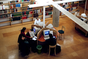 Studenter runt ett studiebord på ett bilbliotek.