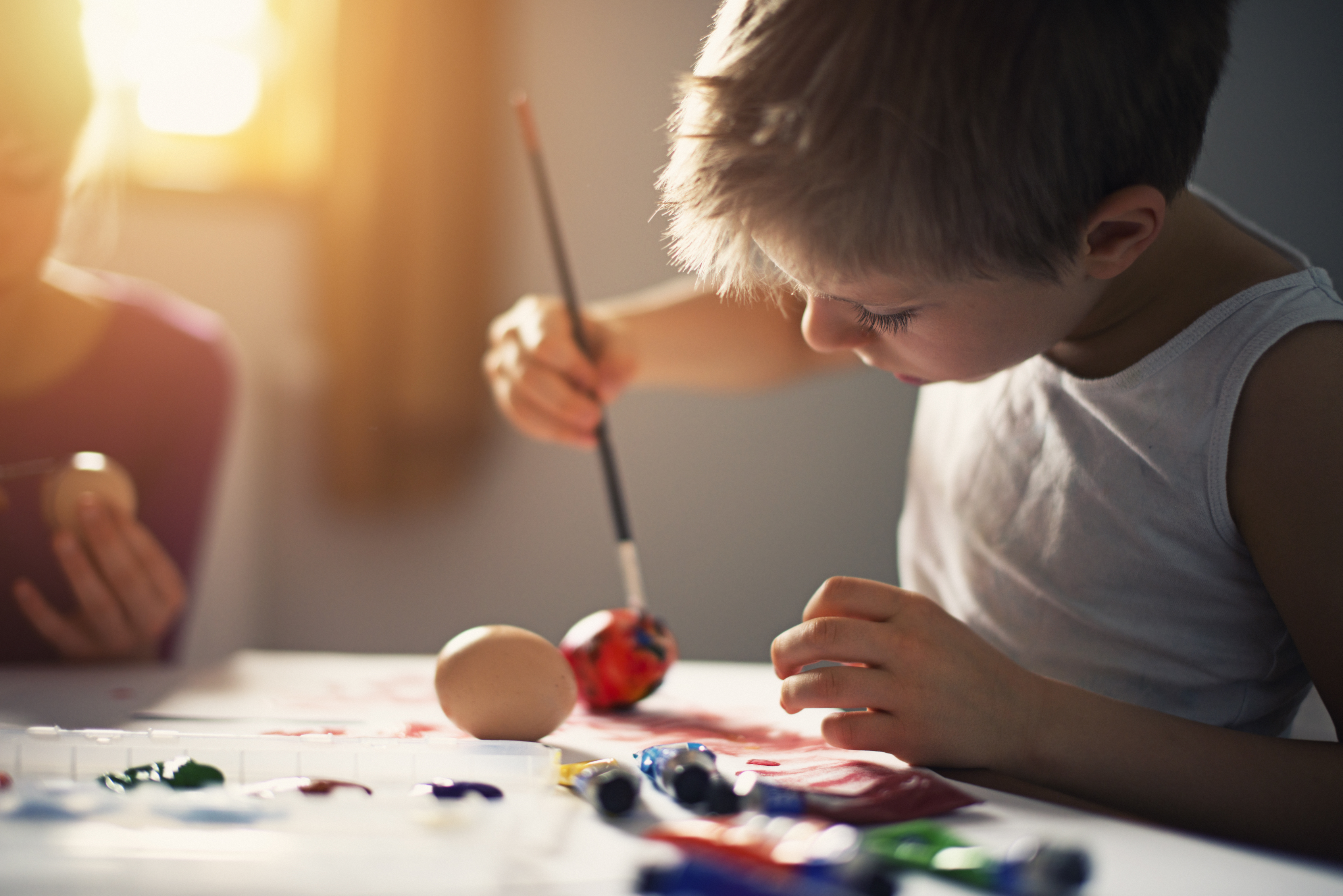 Ett barn sitter fokuserat och målar